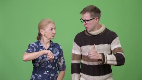 happy grandson giving thumbs up while upset grandmother giving thumbs down
