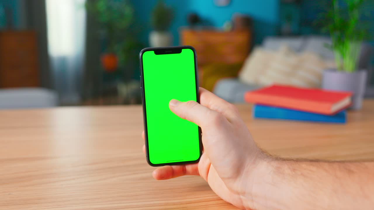 Close-up of a Man Holding and Making Hand Gestures on a Modern Green Mock-up Screen Smartphone. Touching Mobile Phone Chroma Key Screen with a Finger