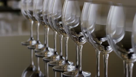 a neat row of empty wine glasses on a reflective surface