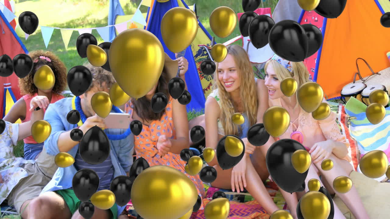 Celebrating with black and gold balloons, friends having outdoor picnic together