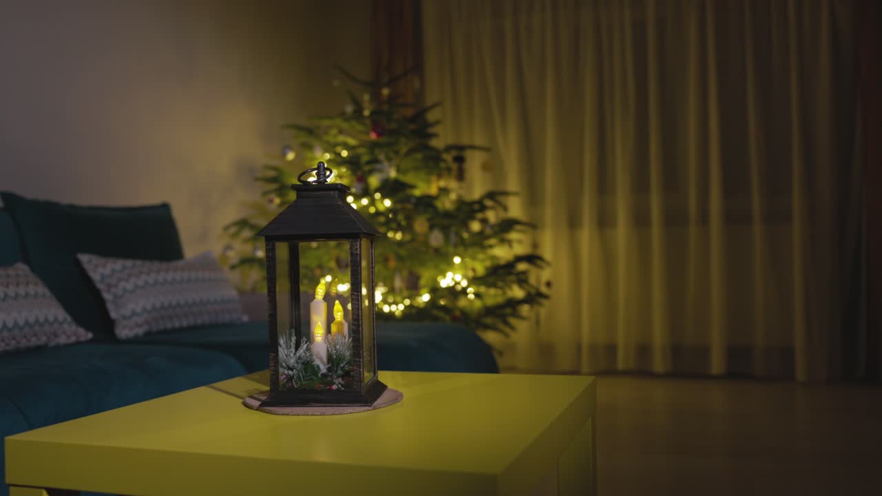 una linterna de vela posicionada cerca del brillante árbol de navidad - toma estática