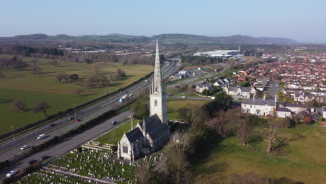 an aerial view of the marble church in bodelwyddan on a sunny morning, flying left to right around the church, denbighshire, north wales, uk