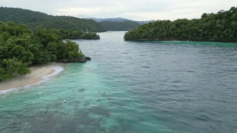 drone footage over shallow reefs and tropical islands revealing a luxury sailboat