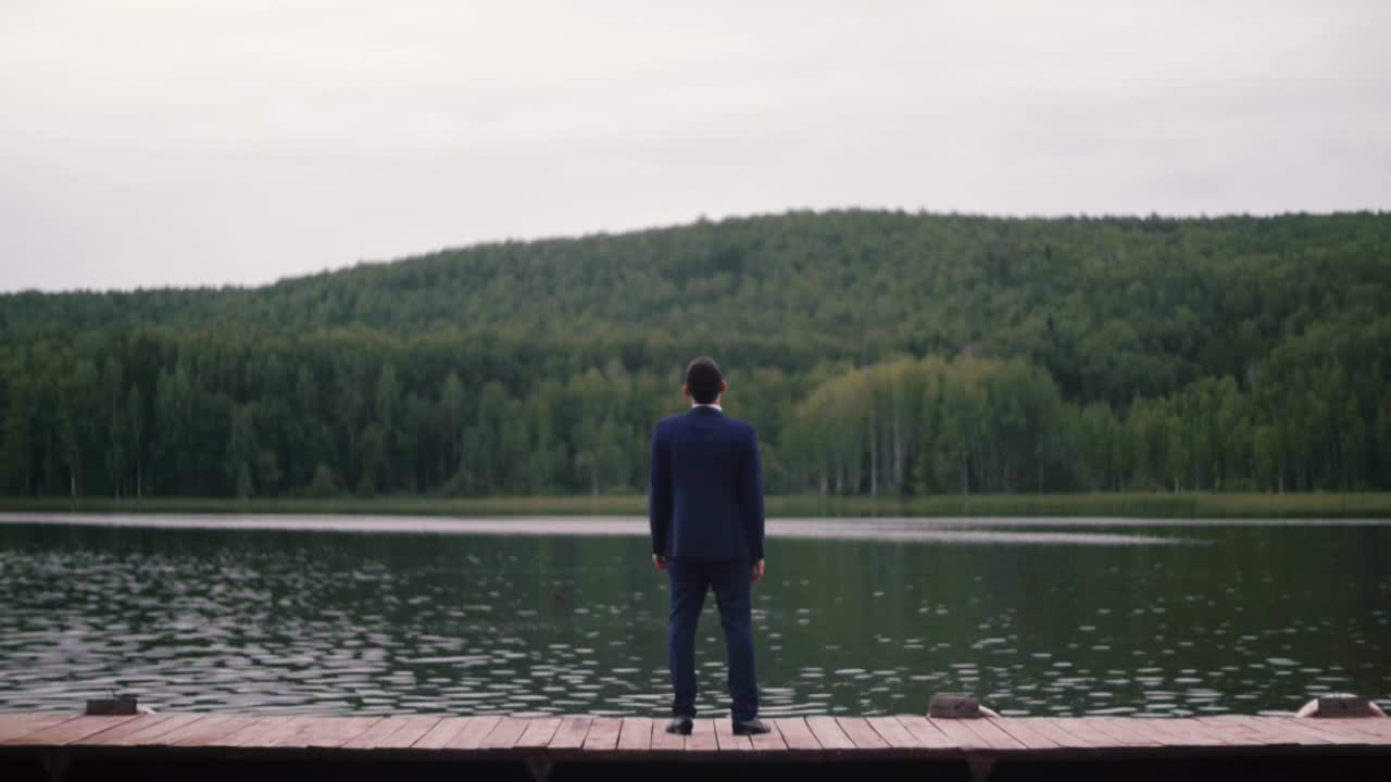 호수 근처 의 항구 에 서 있는 슈트 를 입은 남자
