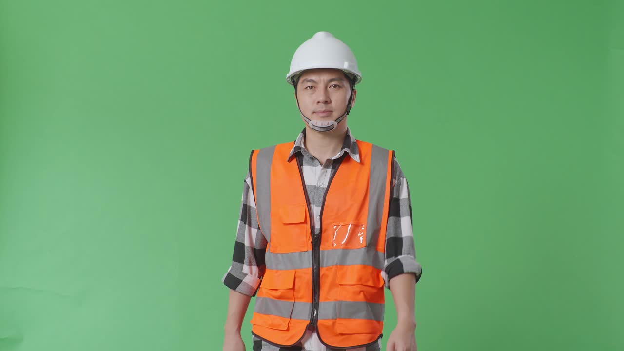 안전 헬을 입은 아시아 남성 엔지니어가 녹색 스크린 배경 스튜디오에서 고 있습니다.