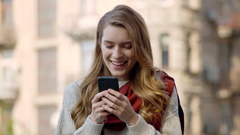 Mujer-Feliz-Enviando-Mensajes-De-Texto-Por-Teléfono-Al-Aire-Libre.-Niña-Sonriente-Recibiendo-Mensaje-En-La-Calle