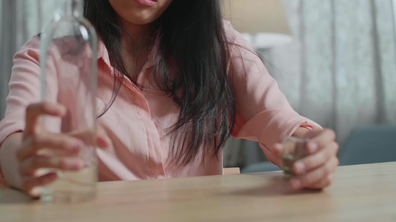 Close Up Of Drunk, Depressed Asian Woman Drinking Vodka Before Using A Fist Smashing The Table At Home