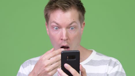 young handsome man using phone and looking shocked