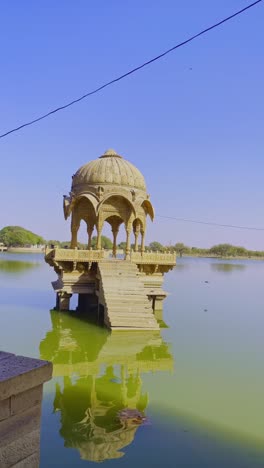 gadsisar lake in jaisalmer sparkles under the golden rajasthan sun, its calm waters reflecting ancient pavilions. this serene offers a peaceful escape amidst the timeless beauty of the desert
