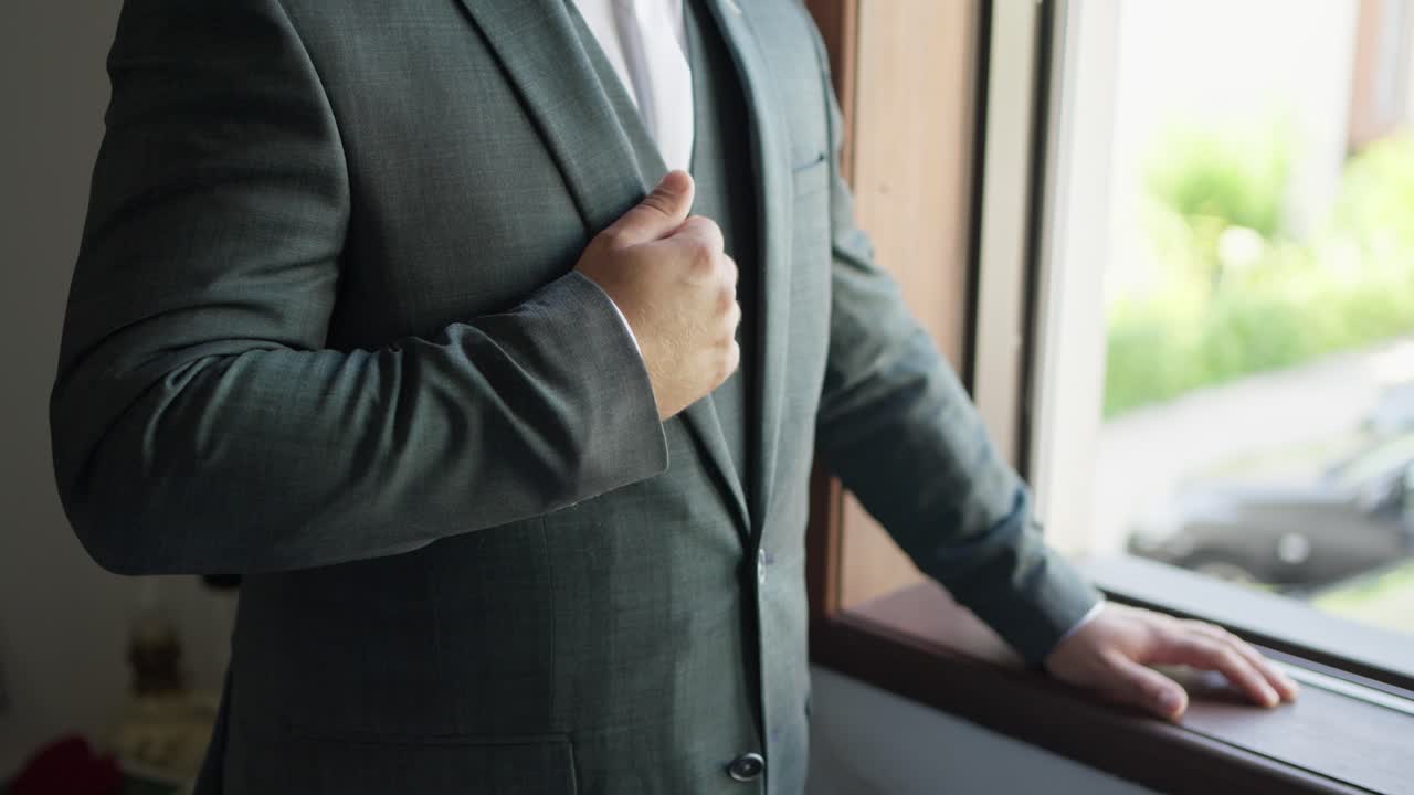 Groom in elegant suit adjusting lapel, preparing for his wedding day
