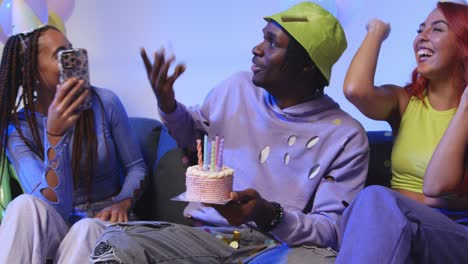 fotografía de estudio de amigos de la generación z celebrando el cumpleaños del hombre con pastel de fiesta y velas sentados en el sofá 1