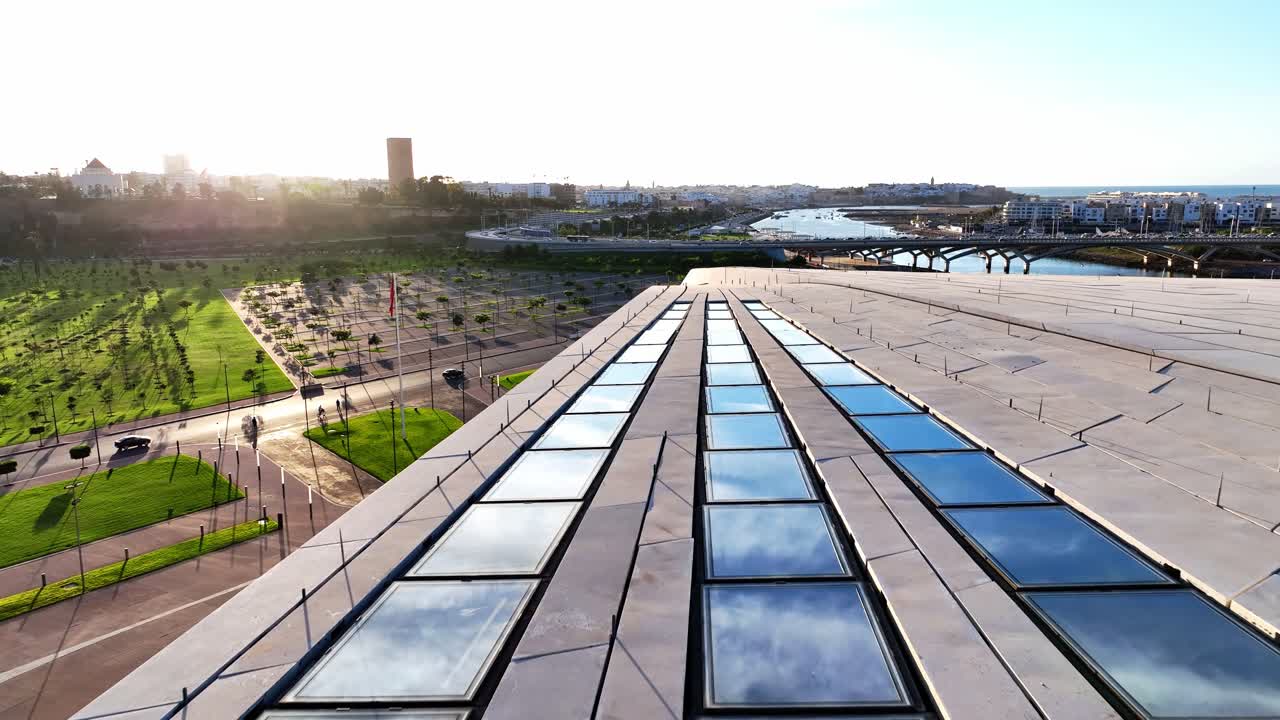 Aerial drone view of the glass roof lines of the Grand Theatre of Rabat with Bouregreg river, bridge and city skyline in the background in Rabat Morocco