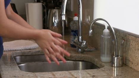 pretty young woman washing hands in the kitchen