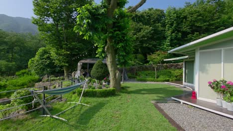 a beautiful view of the luxury glam tree glamping resort in south korea, featuring modern cabins, a relaxing hammock, and a landscaped garden nestled in a peaceful green mountain valley