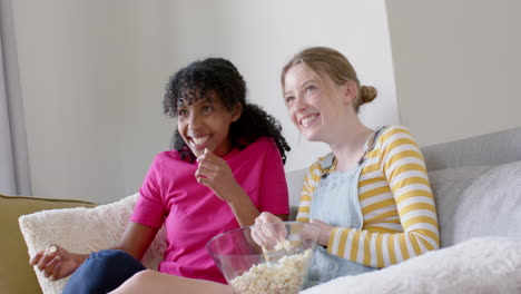 Fröhliche,-Vielfältige-Freundinnen-Im-Teenageralter,-Die-Zu-Hause-Auf-Der-Couch-Popcorn-Essen-Und-Reden,-Zeitlupe