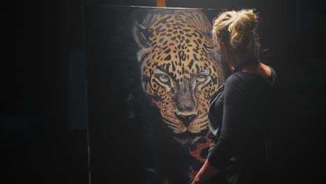 woman looking at painting of a leopard