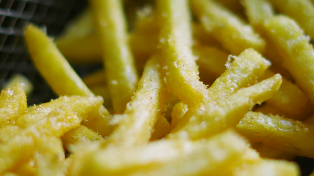 Macro Close Up of Freshly Fried French Fries in Deep Fat Fryer Basket Ready to Serve After Cooking in Hot Oil. Unhealthy Crispy Chips Fast Food