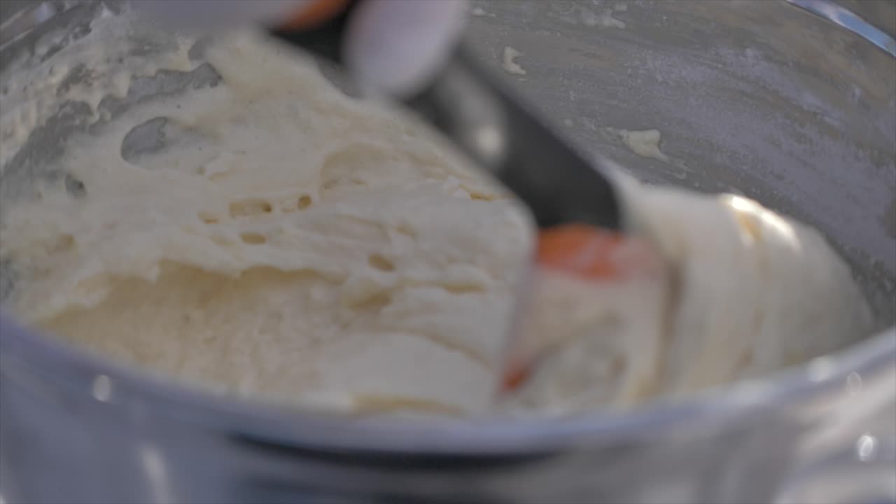 Close up gimbal shot of hands with spatula mixing dough