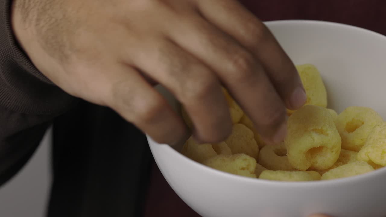 snack24: 한 옥수수 반지를 먹는 젊은이, 그에 소금이 들어있는 간식, 패스트푸드 또는 저크푸드 간식, 건강에 좋지 않은 개념.