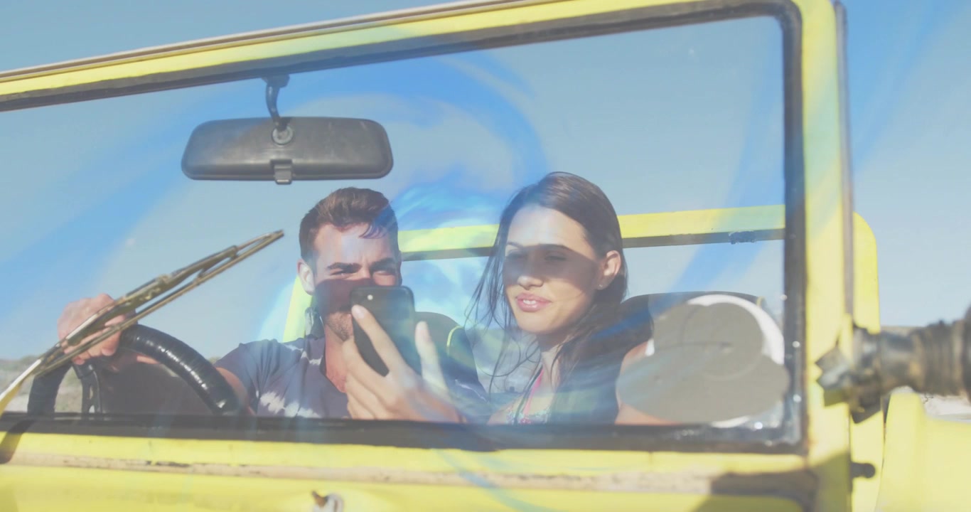 Driver lifting phone showing partner driving yellow car sharing travel pic light leak over faces