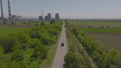 Rising-shot-of-a-car-driving-alongside-a-large-power-plant