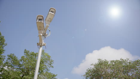 cctv security cameras on pole doing surveillance of area, static upwards shot