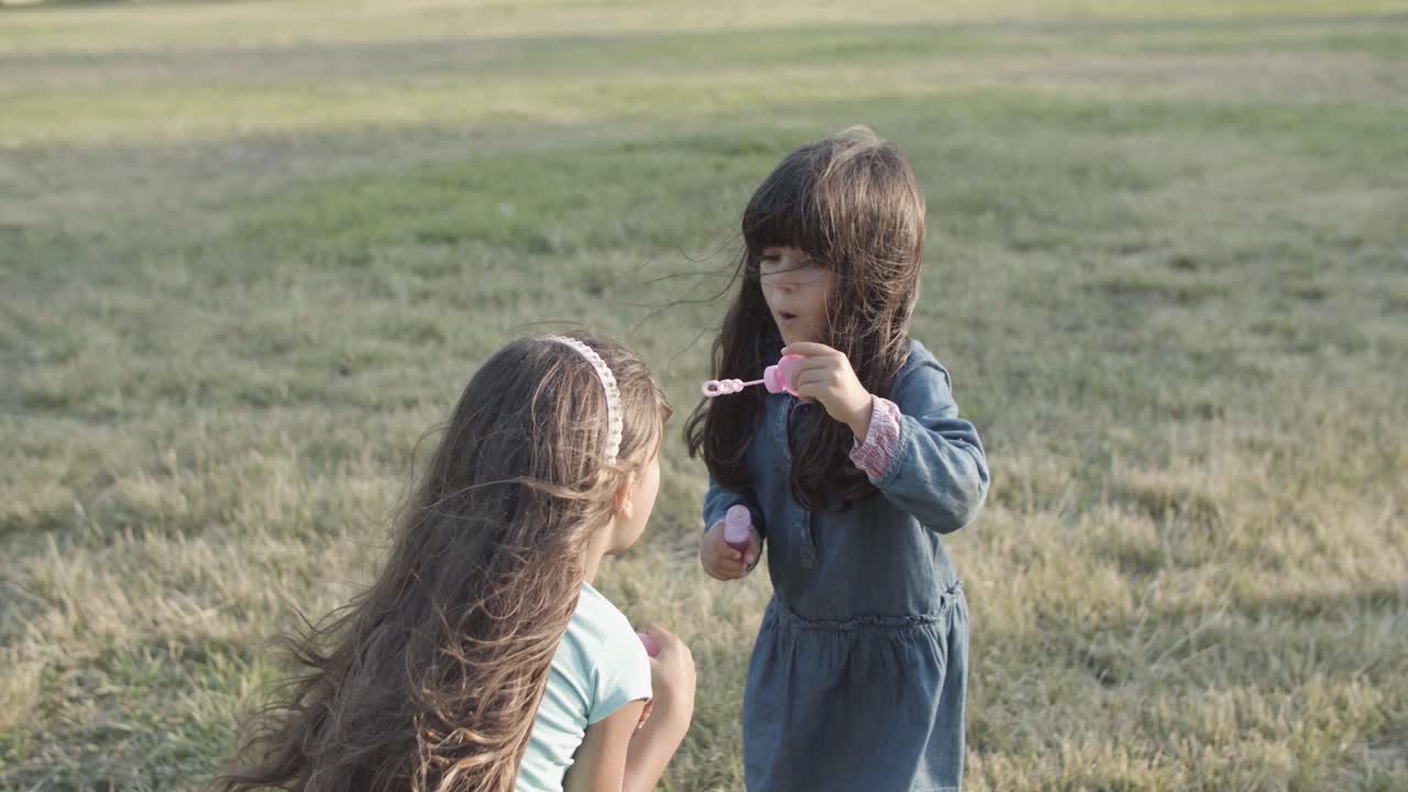 공원에서 서로에게 거품을 불고 있는 귀여운 라틴 소녀들