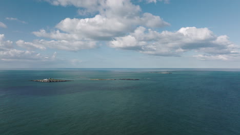 Antena-4k-Acercándose-Al-Faro-De-La-Isla-Farne,-Reino-Unido-En-Una-Tarde-Soleada