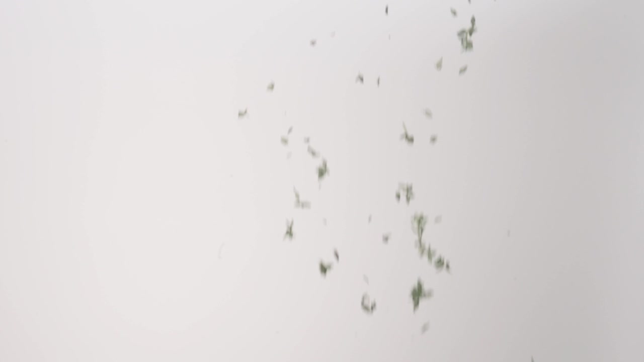 Fresh aromatic Thyme Leaves Pieces raining down on a white backdrop in slow motion close up macro.