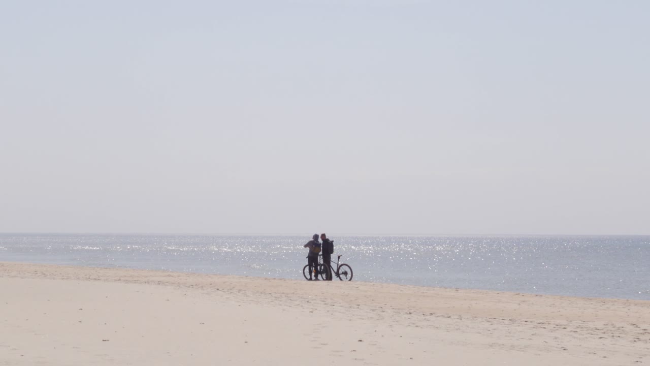 두 명의 자전거 타는 사람이 해변에서 셀카를 찍습니다.