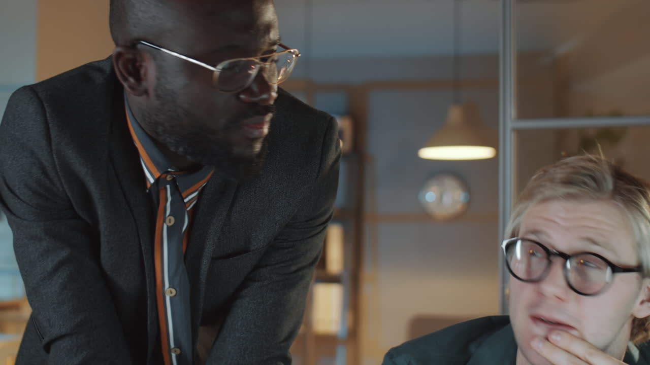 Two Businessmen Discussing Project on Computer in Night Office