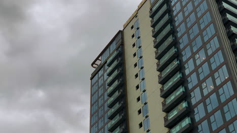 close-up view of a modern apartment building facade featuring glass balconies under an overcast sky.