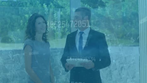 animación de números cambiantes sobre un agente inmobiliario caucásico que muestra una casa a una mujer.