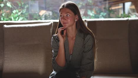 Attractive-young-Caucasian-woman-sitting-down-by-herself-on-the-sofa-while-posing