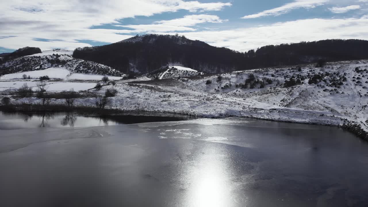 lento aéreo sobre la montaña cubierta de nieve congelada lago soleado día de invierno
