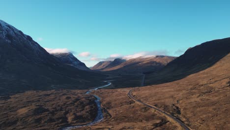 vast scottish highland valley with winding river and road, early morning light, aerial view