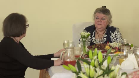 grupo de amigas mayores comiendo y bebiendo juntas en la mesa de cena
