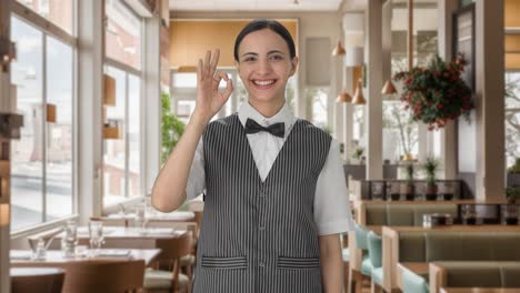 mujer india feliz camarero mostrando una señal de bien