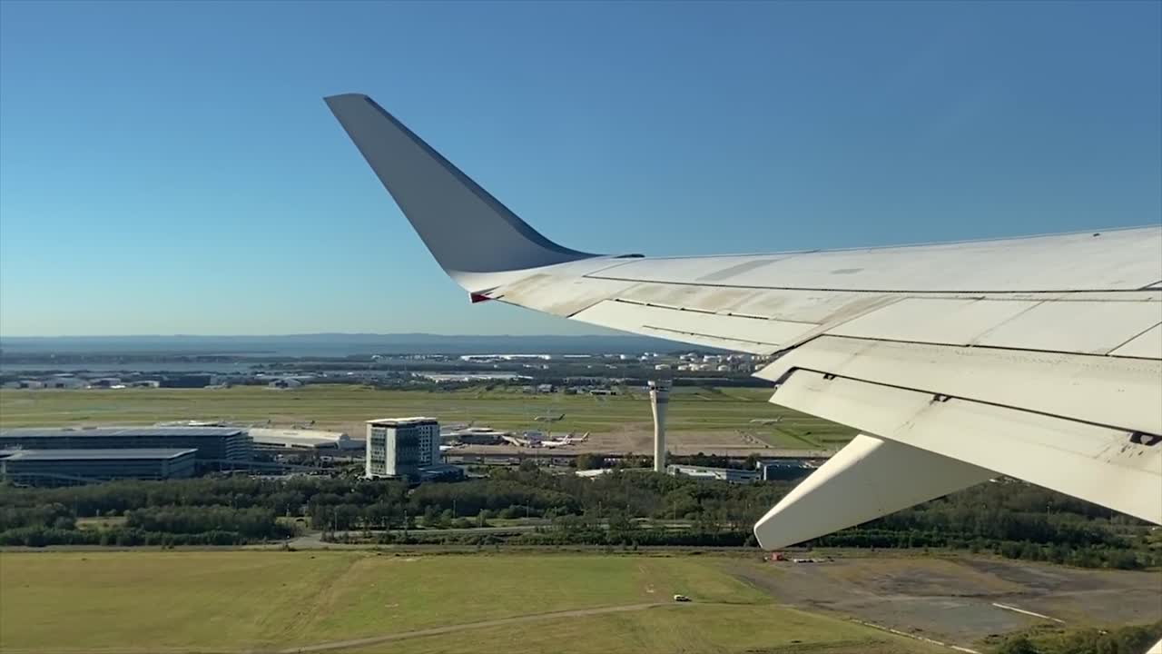 View from an airplane as it takes off from Brisbane Airport, Queensland in Australia, as it climbs steeply to reveal a view of Morton Bay under brilliant blue sky