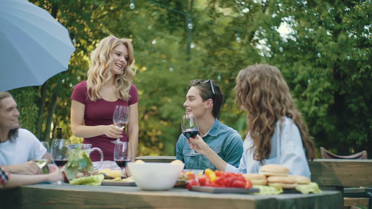 친구들이 야외에서 저녁 파티에서 술을 마시며 건배하고 있습니다.