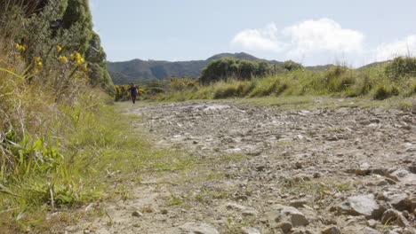 a low angle of a hiker walking towards the camera on a dirt track