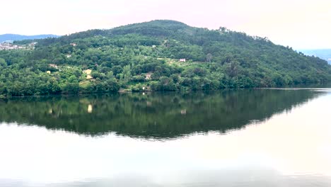 Rio-Douro-on-a-cloudy-day,-its-waters-mirroring-the-romantic-sky-with-mountains-in-the-background