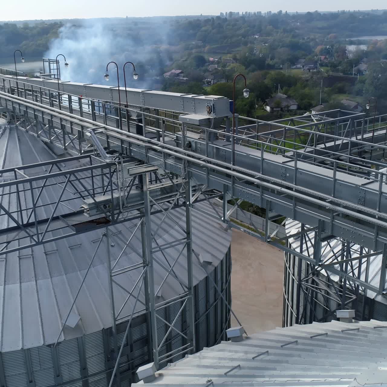 Costruzioni metalliche sopra gli elevatori di grano. Fumo nocivo da una fabbrica agricola inquina l'aria. Vista aerea.
