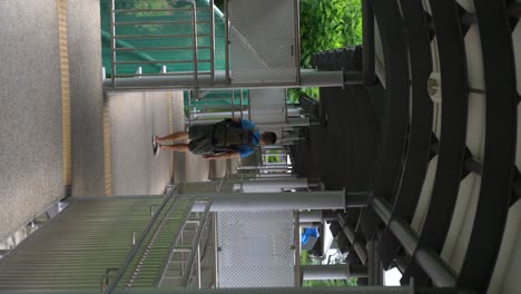 video vertical: hombre chino alejándose en una pasarela cubierta