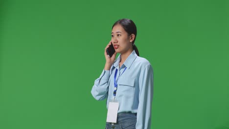 스튜디오의 녹색 화면에서 휴대전화로 대화하는 아시아 사업가의 측면 시각