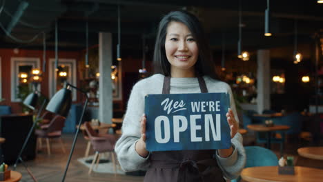woman holding open sign in cafe