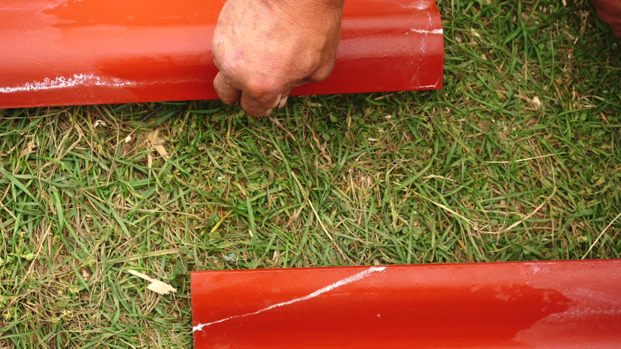 primer plano de la mano del trabajador masculino haciendo mediciones en el techo de acero rojo al aire libre. clip. materiales y equipos para el hogar