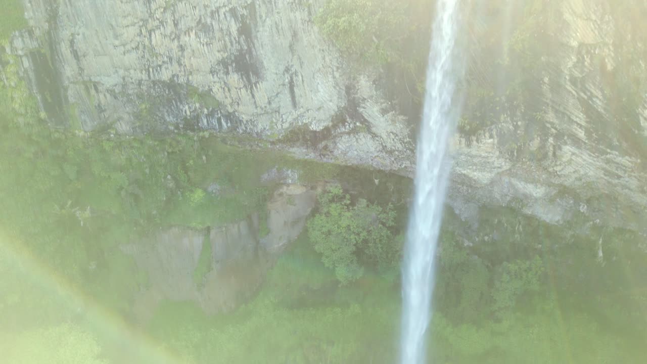 una toma de un avión no tripulado de una cascada rodeada de vida vegetal verde vívido