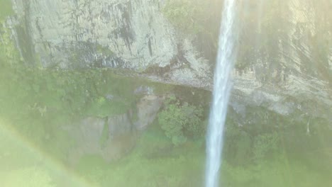 A-drone-shot-of-a-waterfall-surrounded-by-vivid-green-plant-life