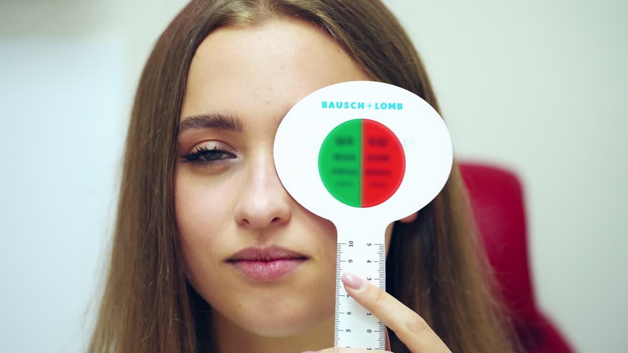 Portrait of a woman with occluder. Beautiful female checking her eyes at ophthalmologist. Girl with one eye closed speaks during vision check up.
